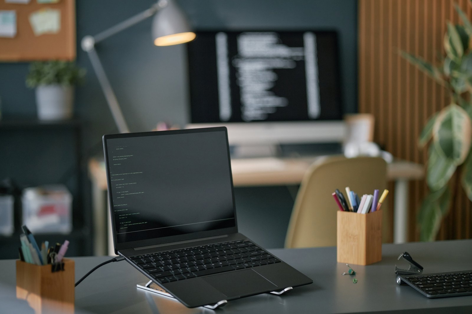 Modern Office Desk Featuring Laptop and Monitor Displaying Programming Code